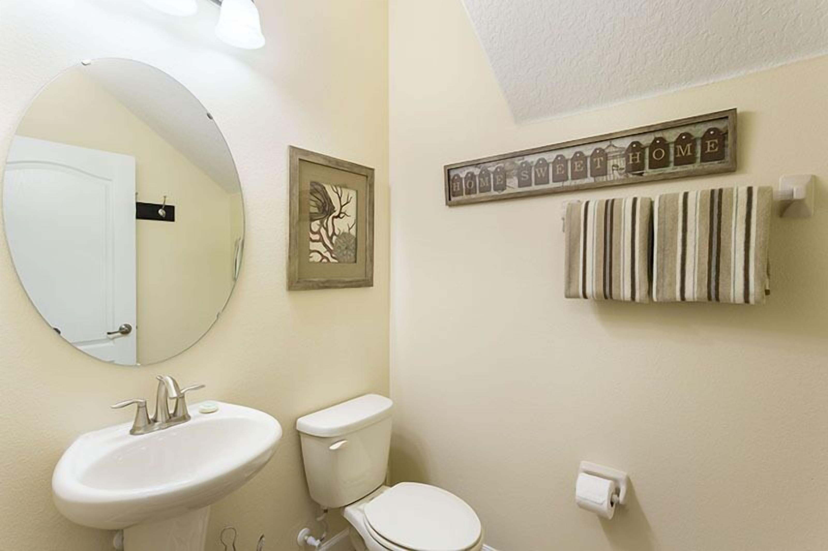 A bathroom with a round mirror, a sink, a toilet, and a towel rack.