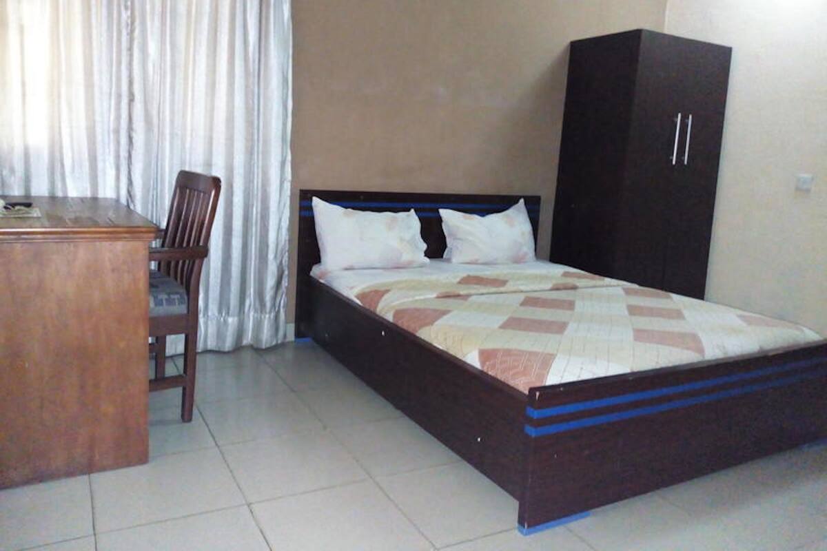 Un dormitorio con cama, escritorio, silla y armario.