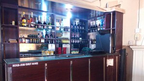 Un espace bar avec des étagères remplies de différentes bouteilles et un comptoir muni d’une caisse enregistreuse.