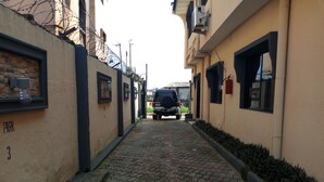 Une ruelle étroite pavée de pierres, un VUS garé et des immeubles de chaque côté.