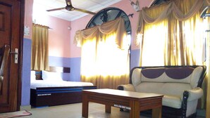 Une chambre d’hôtel avec un lit, un canapé, une table et des rideaux.