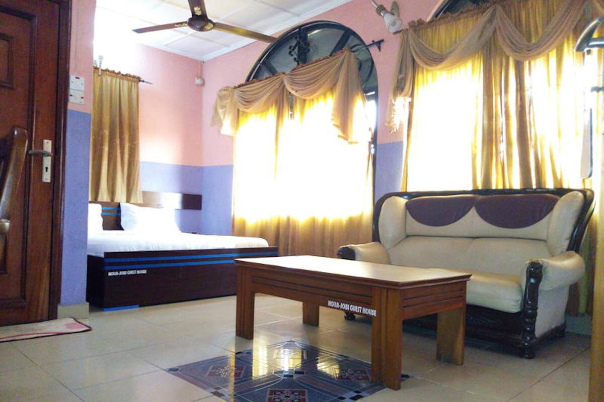 Una habitación de hotel con una cama, un sofá, una mesa y cortinas.