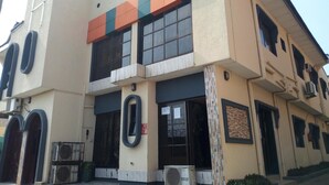 Un bâtiment à deux étages, doté d’une façade beige, de grandes fenêtres et d’une bande orange et verte bien visible.