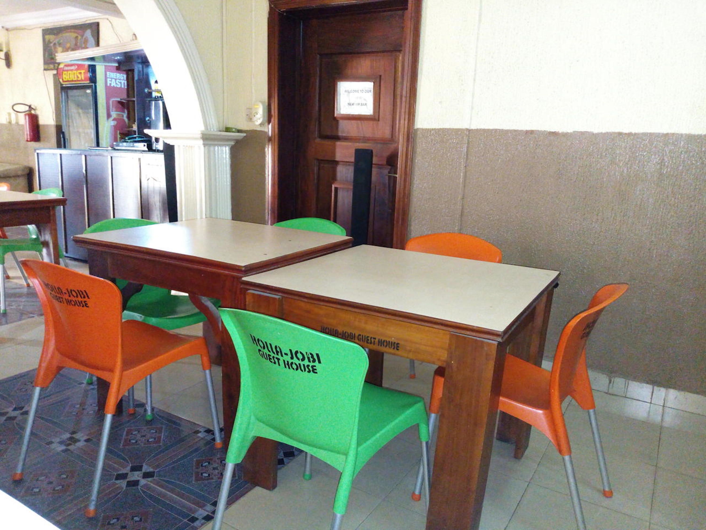 Un área de comedor con mesas y sillas de madera, algunas con la etiqueta 'Hotel Guest House'.