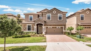 A suburban two-story house with a front garage, a driveway, and a well-maintained lawn. - Je54200 - Champions Gate Resort - 8 Bed 5 Baths Villa (Davenport)