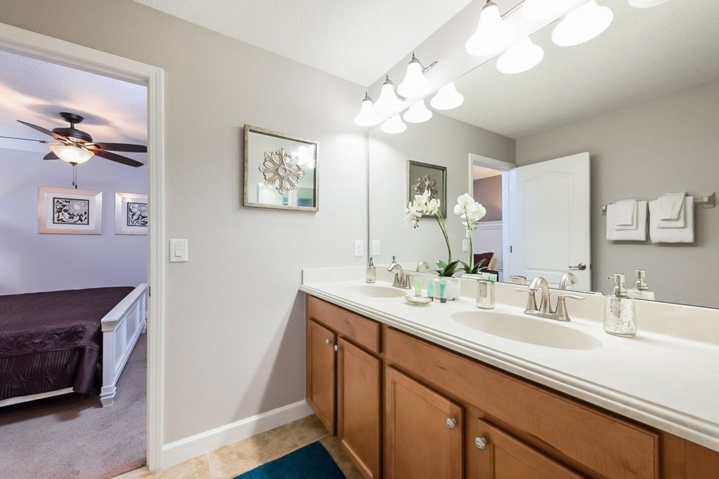 A bathroom with a double sink vanity, a ceiling fan, and a large mirror.