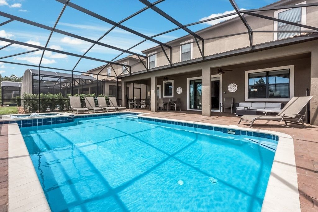 A swimming pool with a covered patio area, lounge chairs, and a pergola structure.
