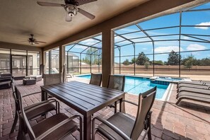 A covered patio area with a pool, outdoor seating, and a view of the surrounding landscape.