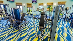 A gym with various exercise equipment, including treadmills and weight machines, and a patterned carpet. - Je54200 - Champions Gate Resort - 8 Bed 5 Baths Villa (Davenport)