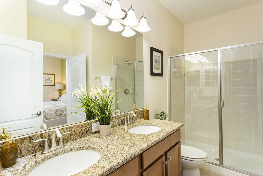 A bathroom with two sinks, a large mirror, and a glass shower enclosure.