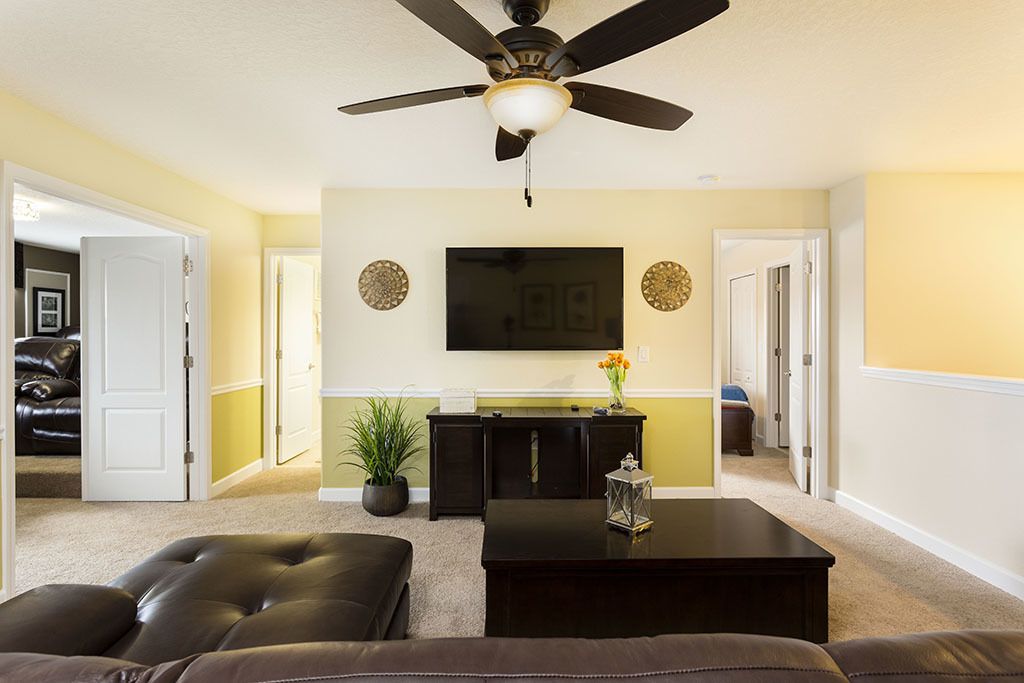 A living room with a ceiling fan, a flat-screen TV, a coffee table, and a sofa.