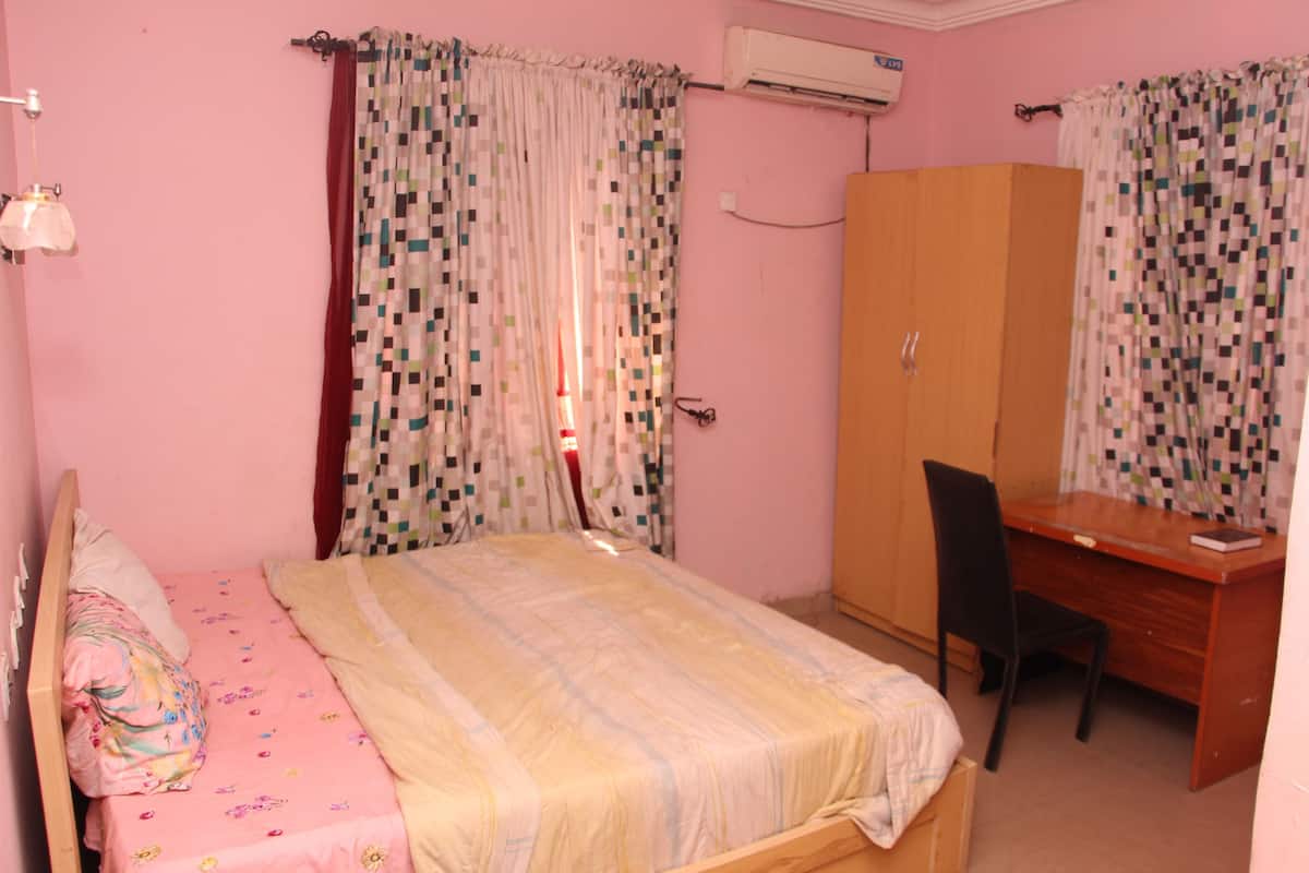 A bedroom with a bed, a desk, and a wardrobe.