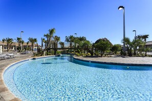Une piscine à bord incurvé, entourée de palmiers et de chaises longues.