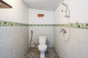 A small bathroom with a toilet, a shower, and a decorative tile border. - Road Beach Villa by Zuzu (Penida Island)