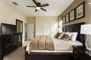 Un dormitorio con cama, cómoda, ventilador de techo y cuadros en la pared.