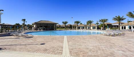 A large outdoor swimming pool with lounge chairs and palm trees.