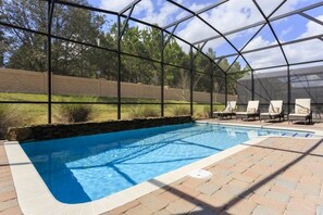 Une piscine couverte avec un mur en pierre et une terrasse en briques.