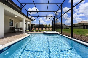 A swimming pool with a glass enclosure, outdoor seating, and a view of surrounding buildings.