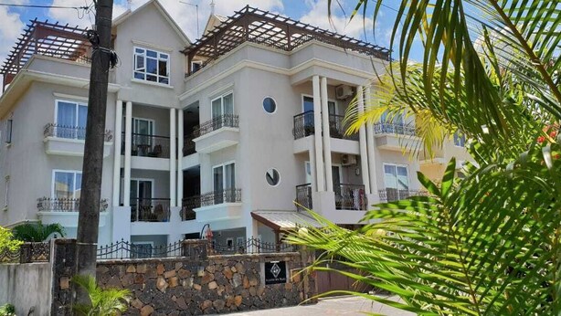 A multi-story residential building with balconies, a stone wall, and a sign indicating a private club. - Northern Pearl Luxury Apartments (Mont Choisy)