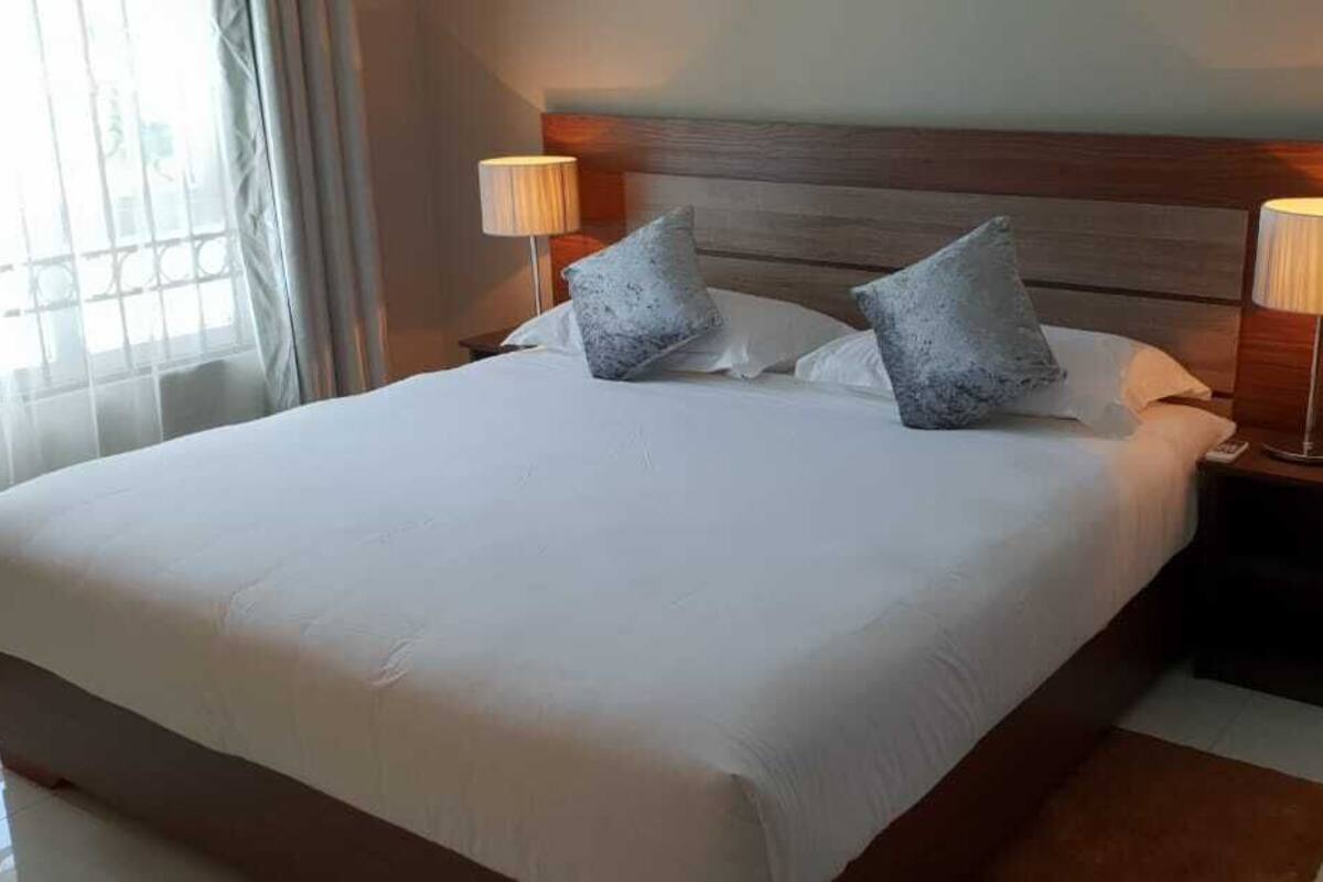 Ein großes Bett mit weißen Bettwäsche, zwei Nachttischlampen und einem Holzkopfstück.