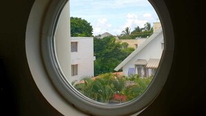 A round window with a view of a residential area, including buildings and greenery. - Northern Pearl Luxury Apartments (Mont Choisy)