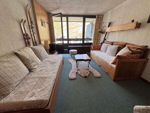 A cozy room with a bed, two sofas, a small table, and a window with a view.