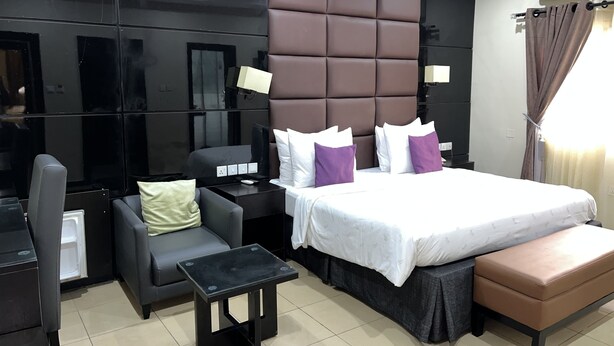 Una habitación de hotel moderna con una cama grande, un sofá, una pequeña mesa y un escritorio con una lámpara.
