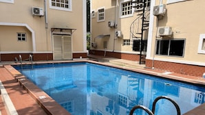 Una piscina rectangular con agua azul cristalina, rodeada por un solado de baldosas.