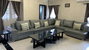Una sala moderna con un sofá modular, una mesa de centro de vidrio y una araña.