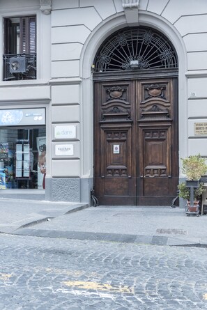 A large, ornate wooden door with a metal grille above it, set in a building with a stone-paved entrance. - B&B Faleron (Naples)