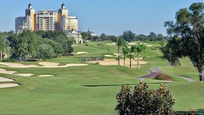Ein Golfplatz mit Bunkern und einem großen Hotel im Hintergrund.