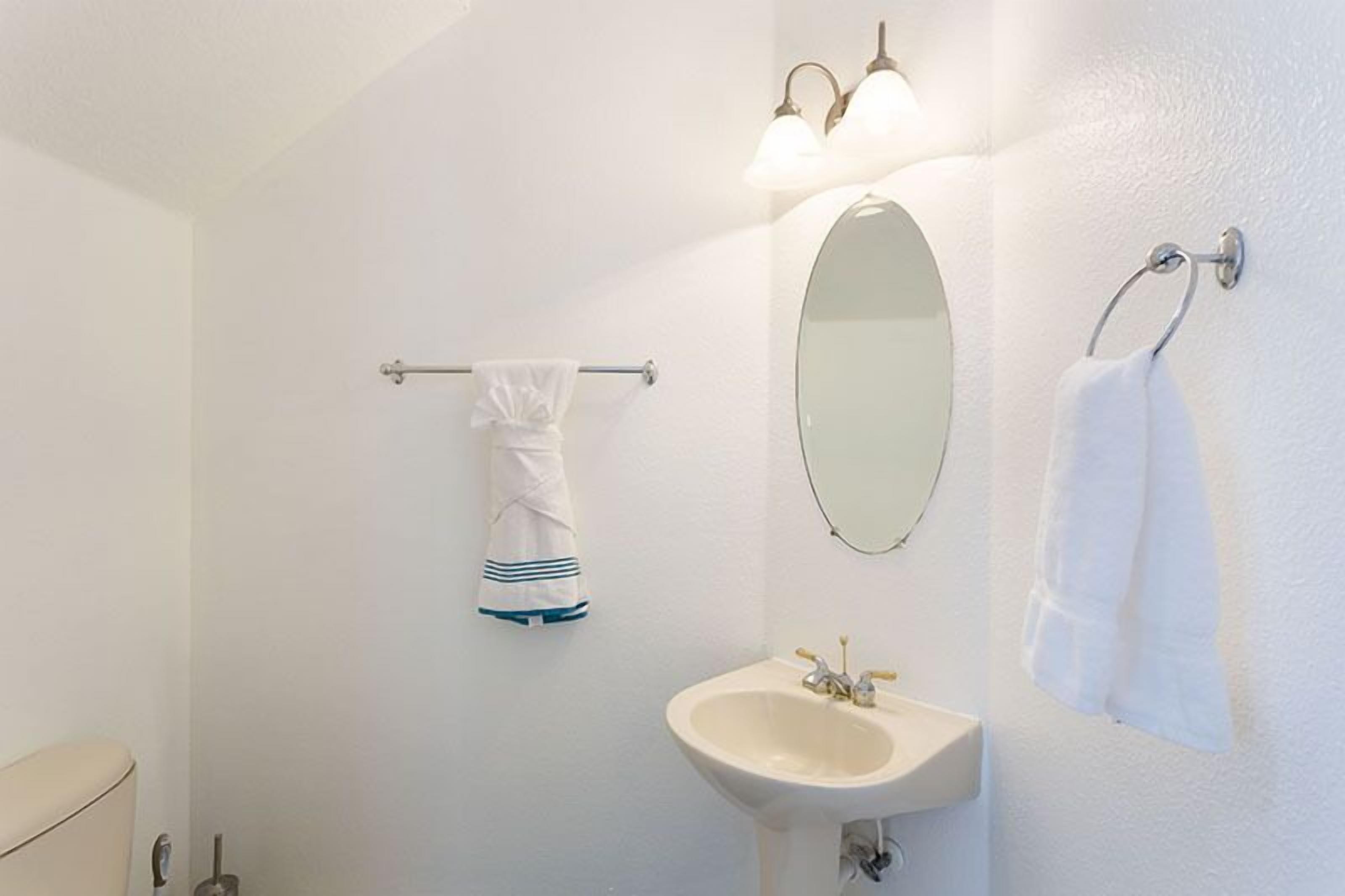 A bathroom with a white sink, a mirror, and two towel racks with white towels.