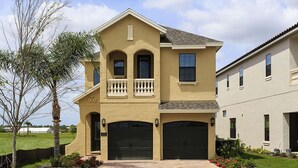 A two-story house with a balcony, a garage, and a well-maintained lawn. - Je52915 - Reunion Resort - 5 Bed 5 Baths Villa (Kissimmee)
