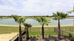 A view of a lake with palm trees and a fence in the foreground. - Je52915 - Reunion Resort - 5 Bed 5 Baths Villa (Kissimmee)