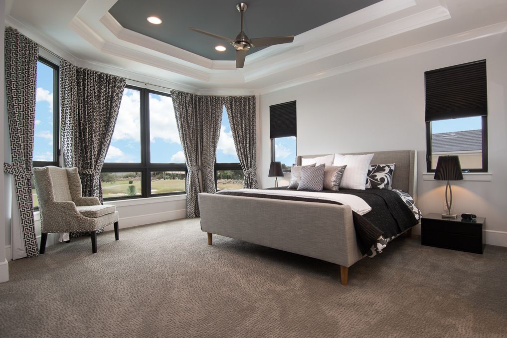 A bedroom with a large bed, a chair, a nightstand, and a ceiling fan.
