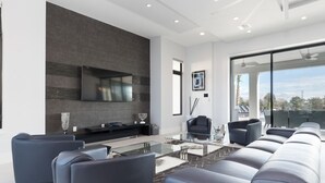 A modern living room with a large TV, leather sofas, a glass coffee table, and a fireplace. - Je52232 - Reunion Resort - 11 Bed 10 Baths Villa (Kissimmee)
