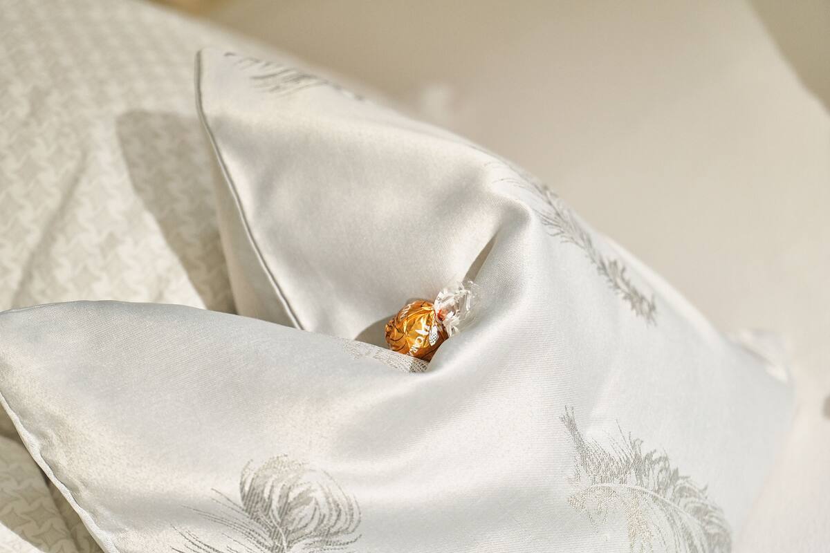A pillow with a floral pattern and a partially visible chocolate bar.
