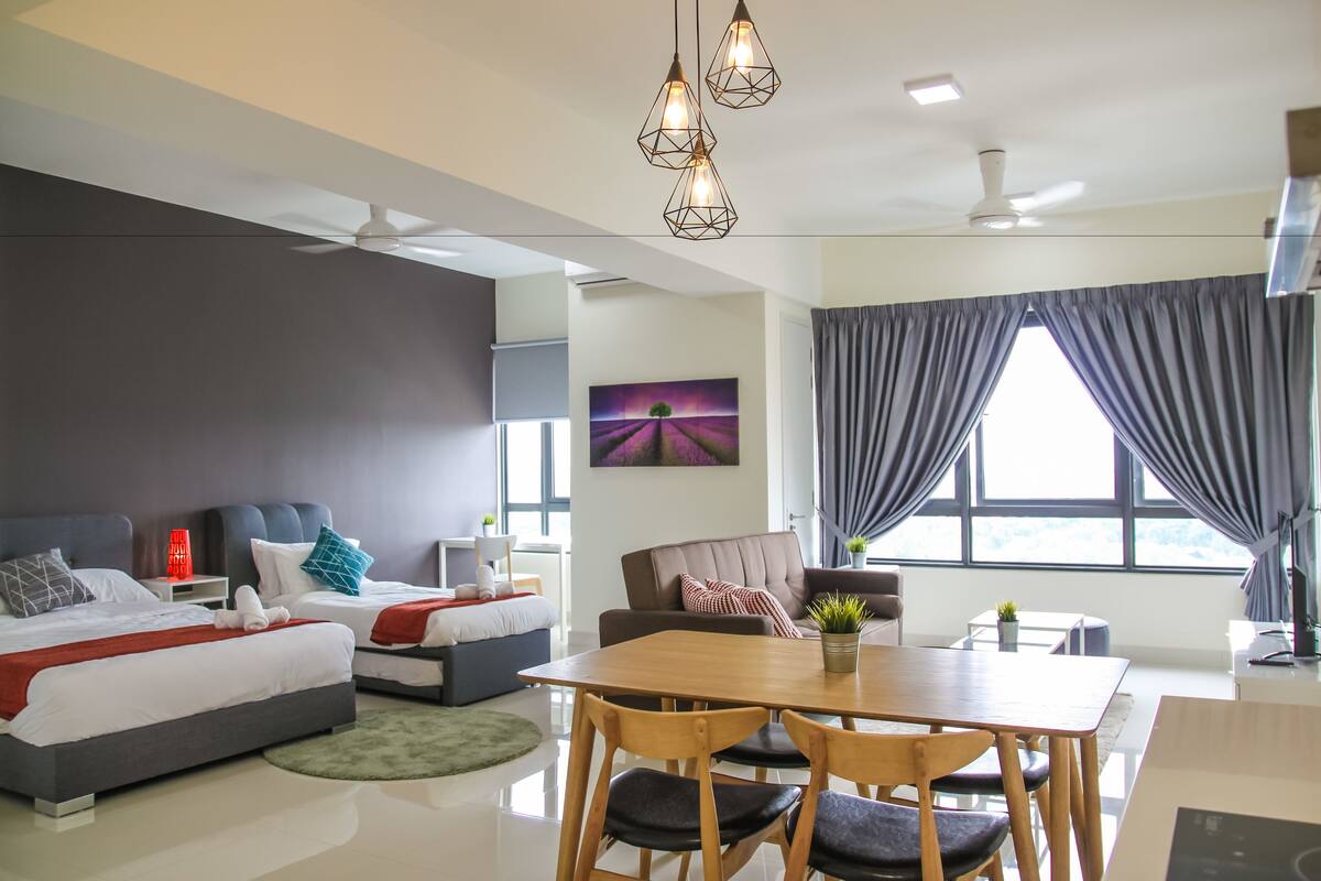 A modern hotel room with a large bed, a dining area, and a view of the outdoors.