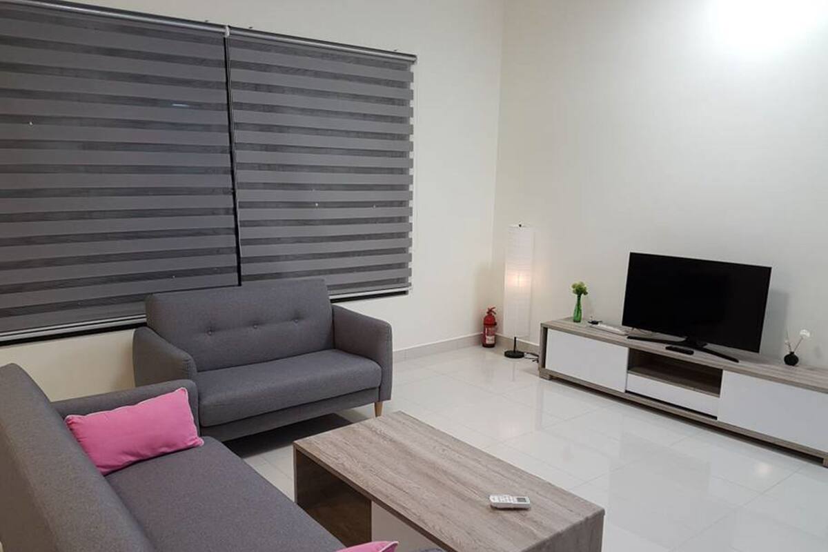 A modern living room with a grey sofa, a wooden coffee table, and a flat-screen TV on a white TV stand.