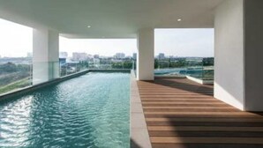 En modern inomhuspool med ett trädäck och glasräcken, som erbjuder utsikt över staden.