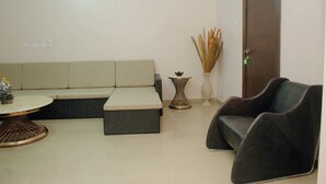 A living room with a sofa, a chair, a small table, and a decorative vase. - mmmHouse Abuja (Abuja)