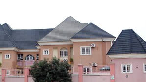 A multi-story residential building with a symmetrical facade, multiple windows, and a gated entrance. - mmmHouse Abuja (Abuja)