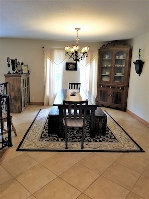 A dining area with a rectangular table and matching bench, set with a table runner and a single plate.