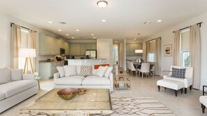 A spacious living room with a sofa, coffee table, and a dining area with chairs.