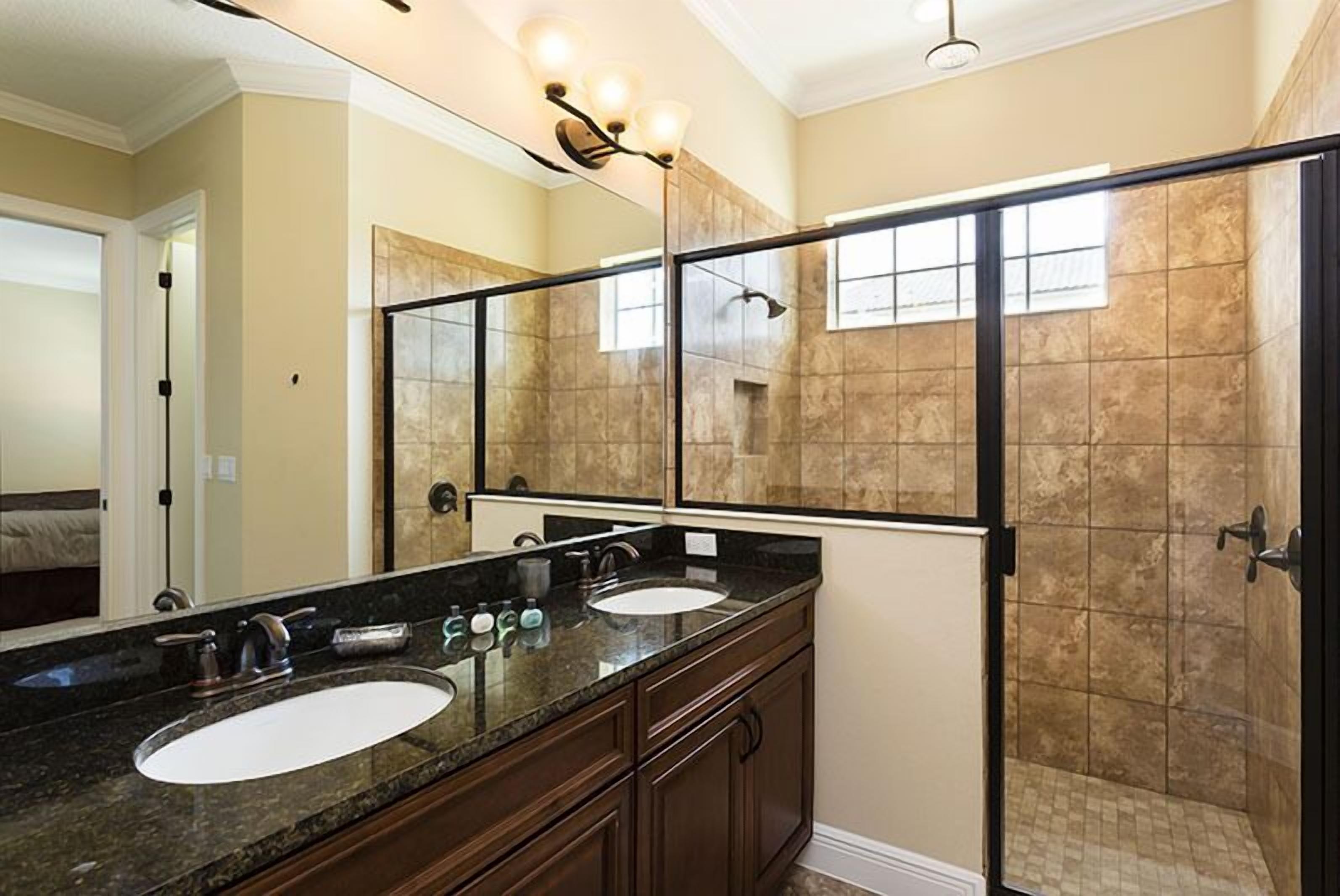 A bathroom with two sinks, a large mirror, and a shower area.