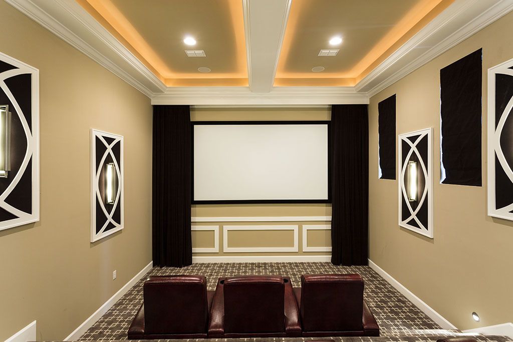 A conference room with a large screen, three leather chairs, and a patterned carpet.