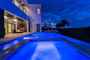 Une maison moderne avec une piscine, au crépuscule.