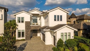 A modern two-story house with a paved driveway, stone accents, and a well-maintained garden.
