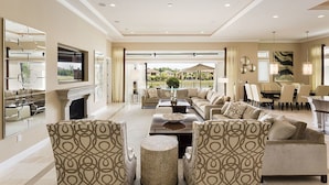 A spacious living room with a fireplace, a large sofa set, and a dining area with a view of the outdoors.