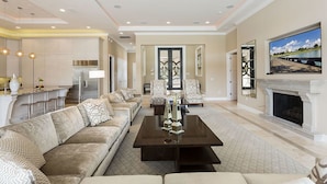 A spacious living room with a large sofa set, a coffee table, and a fireplace.